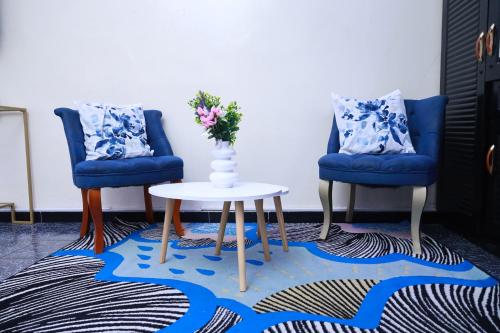 two blue chairs and a table with a vase of flowers at Charmant logement plage Yoff Dakar in Yof
