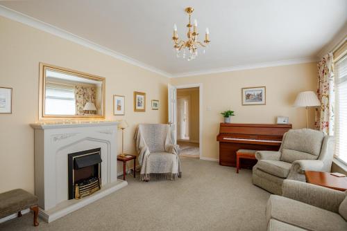 a living room with a fireplace and a piano at The Burrow, a Spacious Bungalow in Heart of NI in Templepatrick