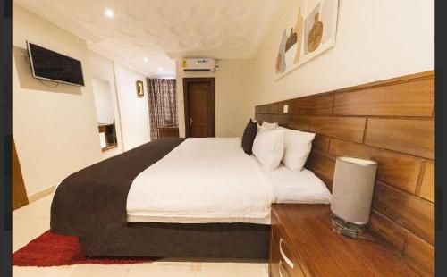 a bedroom with a large bed with a wooden headboard at Airport West Hotel in Accra