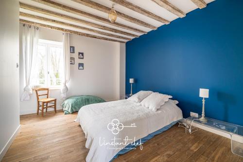 ein Schlafzimmer mit einer blauen Wand und einem Bett in der Unterkunft Maison cosy proche du Mans avec jardin et BBQ - l'instant clef in Parigné-lʼÉvêque