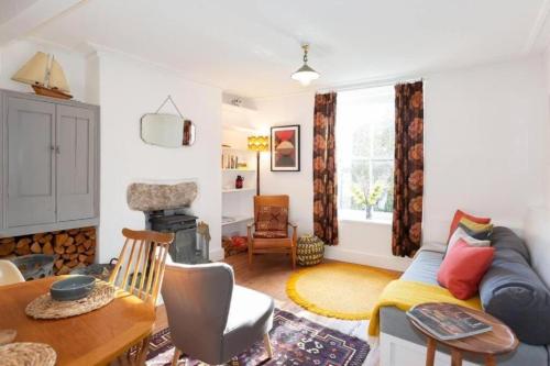 a living room with a couch and a table at Janies Cottage~ Mousehole~Eclectic Interiors & Vintage Charm in Mousehole