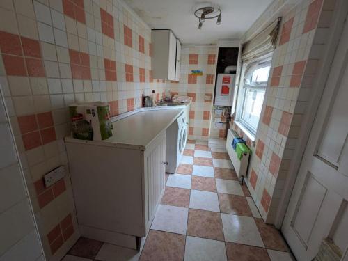 a kitchen with a tiled floor and a refrigerator at Gordon Avenue Guest House HA7 London in Busheyheath
