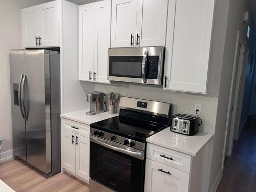 a kitchen with white cabinets and a stainless steel refrigerator at Brand new home near beautiful beaches in Port Charlotte