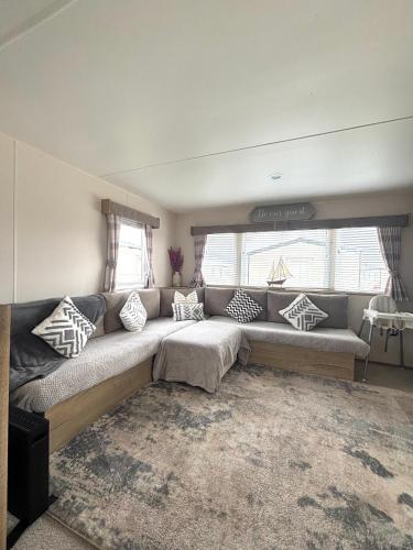 a living room with a large couch in front of a window at Berwick Holiday Park Haven in Berwick-Upon-Tweed