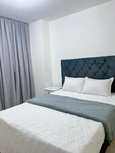 a bedroom with two beds and a blue headboard at apartamento en la floresta in Medellín