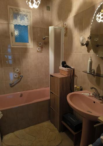 La salle de bains est pourvue d'une baignoire rose et d'un lavabo. dans l'établissement L'Ardéchois, à Vals-les-Bains