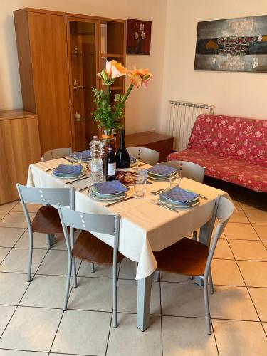a dining room table with chairs and a vase with flowers at RESORT VILLAGE AQUA MARINA FAMILY - Daily Rooms Tidying - CocktailsBar- Pet Friendly - with Hypermarket - Delivery Restaurant-Pizzeria - Room Breakfast with supplement - Ultra Fast Wi-Fi - Play Area for children - Olympic Swimming Pool - Parking in Caorle