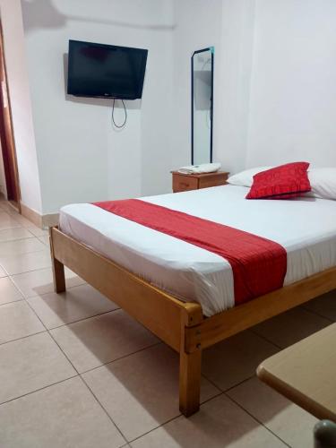 a bedroom with a bed and a tv on a wall at Hospedaje Casa Amazónica Iquitos in Iquitos