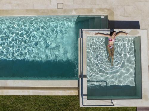 a woman swimming in a swimming pool at Almi-Cove Hilltop Villas in Almirida