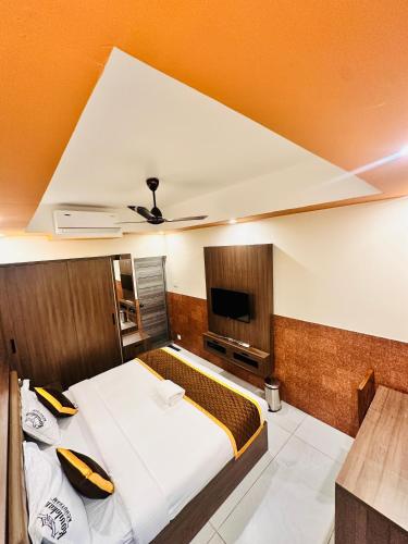 a bedroom with a large bed and a tv at Kovilakam Achutham in Guruvāyūr