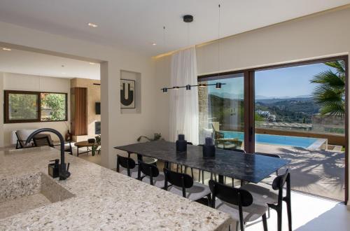 a kitchen and dining room with a table and a large window at Almi-Cove Hilltop Villas in Almirida