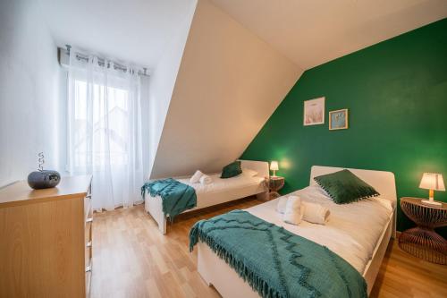 - une chambre avec 2 lits et un mur vert dans l'établissement Le Terra Verde - Terrasse et Jardin, à Haguenau