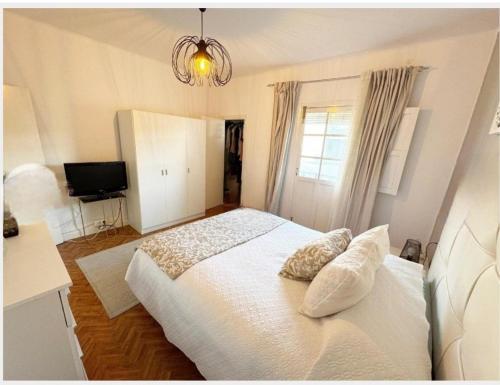 a bedroom with a white bed with pillows and a television at La Casita de Ronda in Ronda