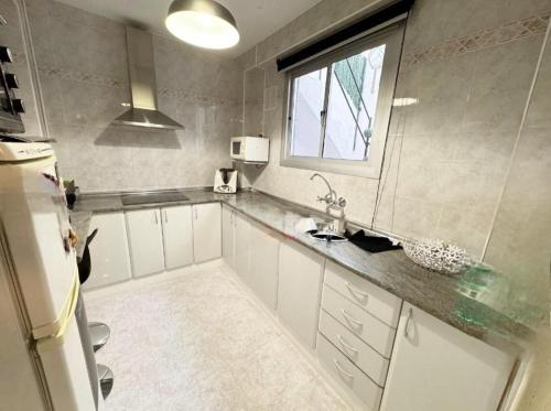 a kitchen with white cabinets and a window at La Casita de Ronda in Ronda