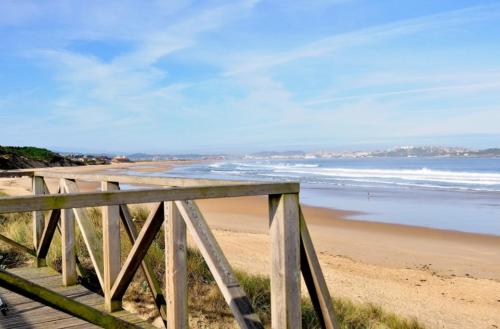 a wooden boardwalk leading to a beach with the ocean at La Casita del Montañes in Liérganes
