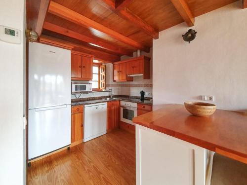 a kitchen with a white refrigerator and wooden cabinets at La Casita del Montañes in Liérganes