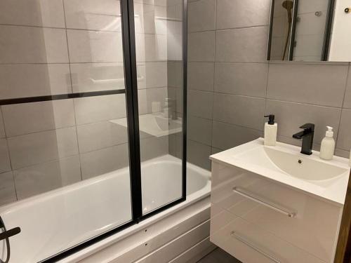 une salle de bain blanche avec un lavabo et une douche dans l'établissement Le Cocon des Cîmes, aux Contamines-Montjoie