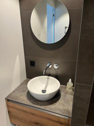 a bathroom with a white sink and a mirror at Neue helle Wohnung mit Bergblick am Eingang der Jungfrau Region und Berner Oberland in Aeschi bei Spiez