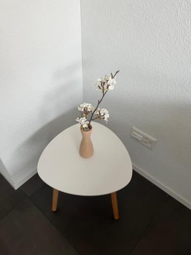 a white table with a vase with flowers on it at Neue helle Wohnung mit Bergblick am Eingang der Jungfrau Region und Berner Oberland in Aeschi bei Spiez