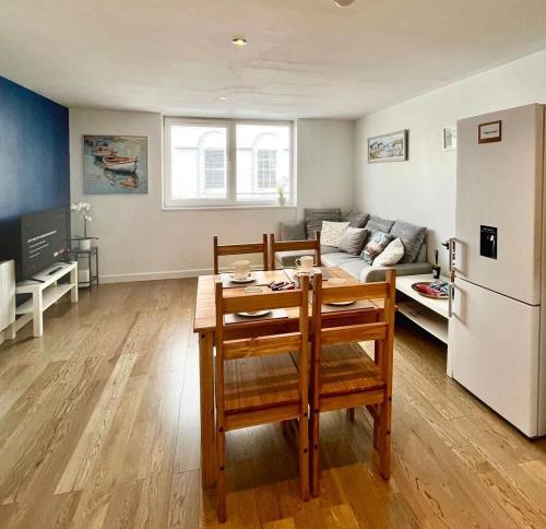 cocina y sala de estar con mesa y nevera en Modern Flat overlooking High St, en Andover