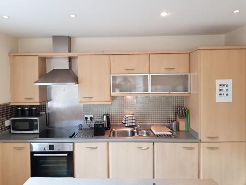 a kitchen with wooden cabinets and a sink at Solihull Centre Apartments in Solihull