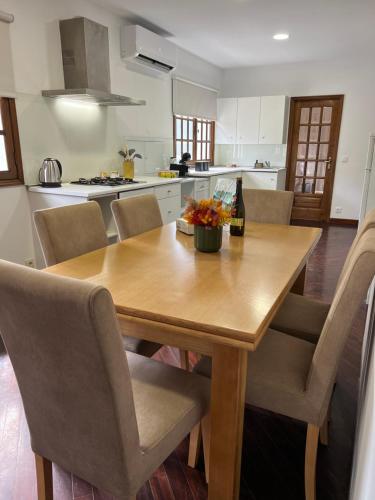 a kitchen with a wooden table with chairs and a bottle of wine at Casa São Domingos in Lousada