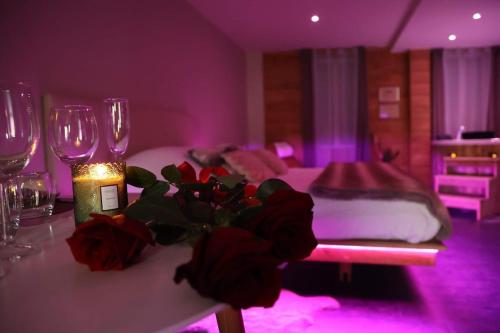 Cette chambre comprend une table avec des verres à vin et un lit. dans l'établissement Suite Charme Loveroom La Manova Spa&Sauna, à Saint-Martin-dʼAuxigny