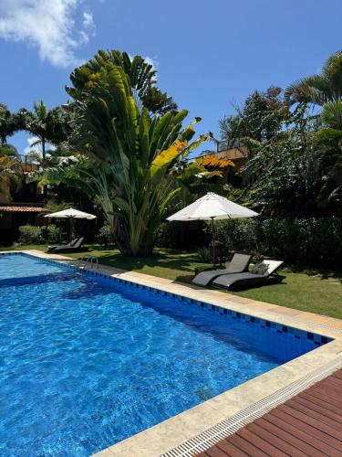a swimming pool with chairs and umbrellas in a yard at Apartamento A-11 Pipa Beleza Resort in Pipa