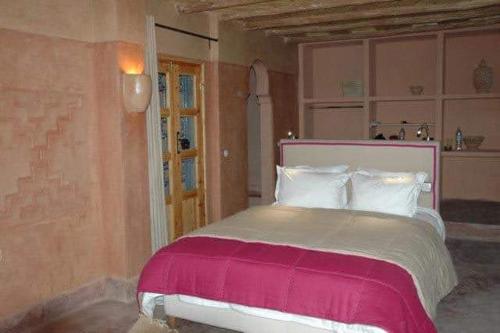 a bedroom with a large bed with pink and white sheets at Kasbah Alami in Kalaat MGouna