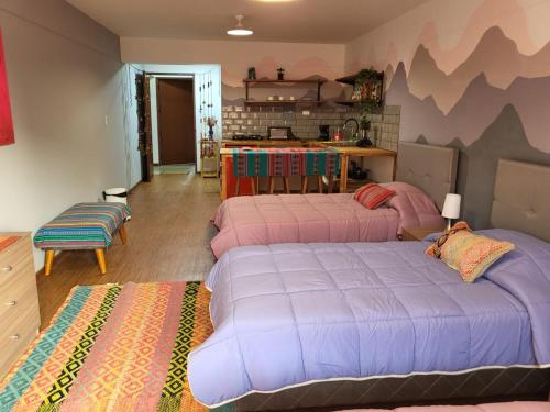 a bedroom with two beds and a kitchen in the background at Alojamiento San Francisco - Apartamentos y habitaciones in Lima
