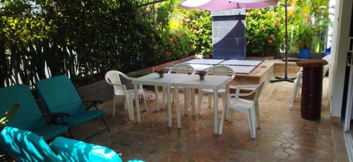 a white table and chairs on a patio with an umbrella at Hermoso Apartasol!! cerca a Plaza Principal, Aire Acondicionado, Vista a la Piscina in Santa Fe de Antioquia