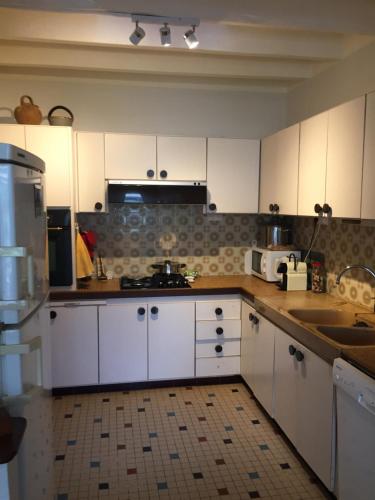 une cuisine avec des armoires blanches et des appareils électroménagers blancs dans l'établissement Maison familiale Les Boucs, à Rouffignac