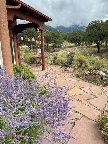 a patio with chairs and purple flowers next to a building at Crestone Adobe Vista Manor in Crestone