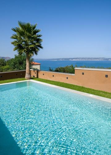 a swimming pool with a palm tree and the ocean at Almi-Cove Hilltop Villas in Almirida