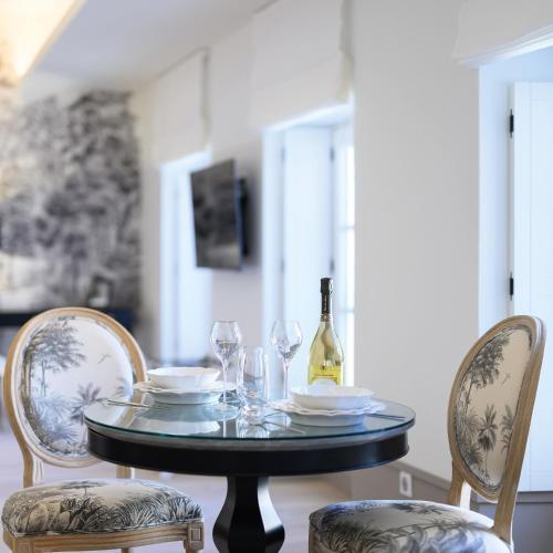 - une table avec une bouteille de vin et 2 chaises dans l'établissement Les Suites BB, Champagne Besserat de Bellefon, à Épernay