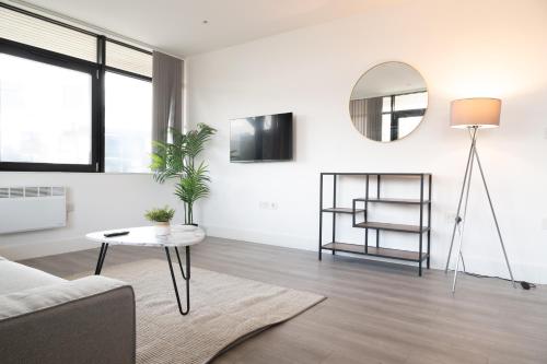 a white living room with a table and a mirror at Charles Hope London Brentford in Brentford