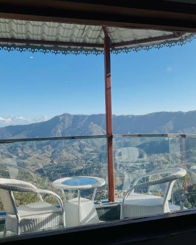 a view of a table and chairs on a balcony at Satyam Shivam Sundaram in Mukteswar