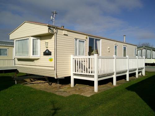 a mobile home with a porch and a white fence at Golden Sands Willerby GS 6 Berth Panel heated FREE WIFI in Ingoldmells
