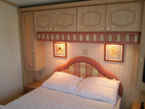 インゴールドメルズにあるGolden Sands Willerby GS 6 Berth Panel heated FREE WIFIの木製のヘッドボードが付いたベッドのある寝室