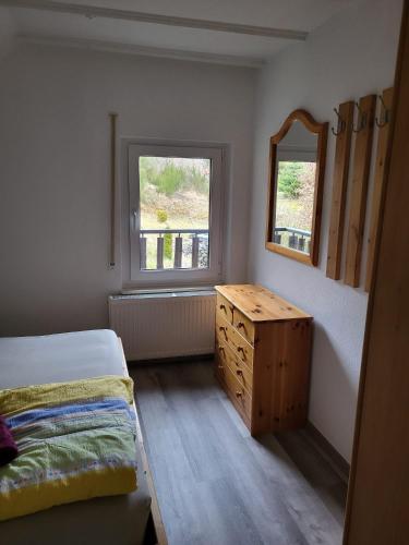 a bedroom with a bed and a dresser and a window at Haus Petra in Stadtkyll