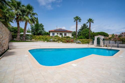 une piscine devant une maison avec des palmiers dans l'établissement Luxueux studio piscine, à Sainte-Maxime