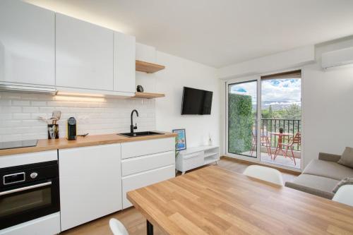 une cuisine avec des placards blancs et une salle à manger avec un balcon dans l'établissement Luxueux studio piscine, à Sainte-Maxime