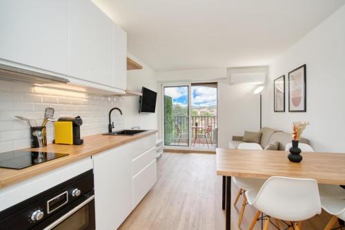 une cuisine avec des armoires blanches et une table et des chaises dans l'établissement Luxueux studio piscine, à Sainte-Maxime