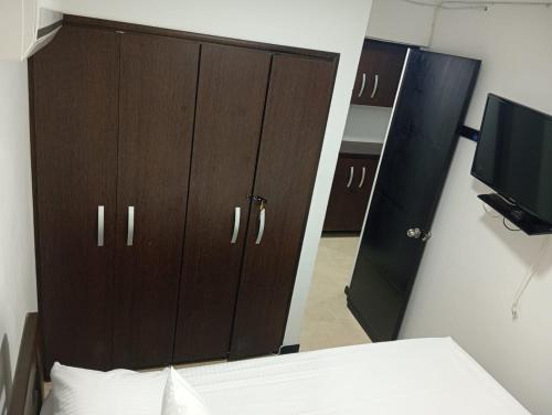a bedroom with a large brown cabinet and a television at Hermoso Apartasol!! cerca a Plaza Principal, Aire Acondicionado, Vista a la Piscina in Santa Fe de Antioquia