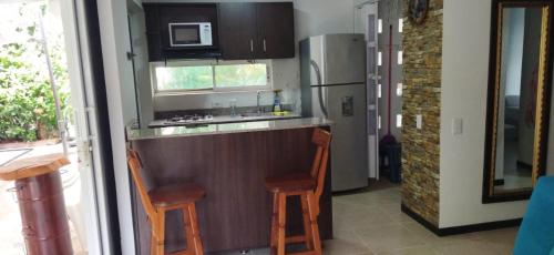 a kitchen with a bar with two stools and a refrigerator at Hermoso Apartasol!! cerca a Plaza Principal, Aire Acondicionado, Vista a la Piscina in Santa Fe de Antioquia