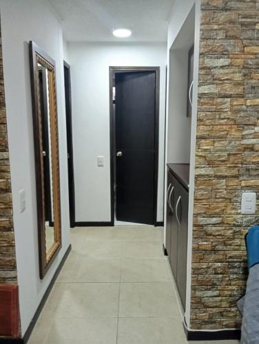 a hallway with a black door and a stone wall at Hermoso Apartasol!! cerca a Plaza Principal, Aire Acondicionado, Vista a la Piscina in Santa Fe de Antioquia
