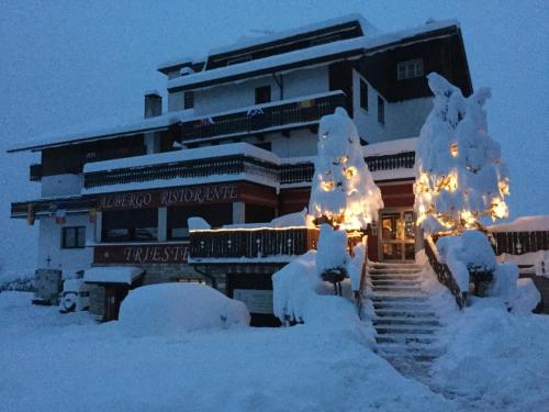 a building covered in snow with christmas lights at Albergo Trieste in Tambre dʼAlpago