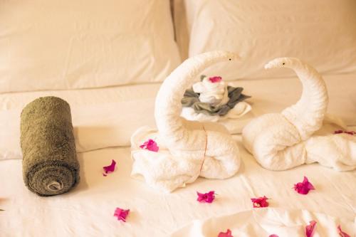 a bed with two white towels and pink butterflies at Ari Paradise in Hangnaameedhoo