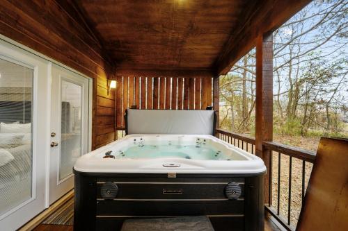 une baignoire installée au milieu d'une terrasse couverte dans l'établissement The Modern Luxurious Mystic Love Cabin, à Broken Bow