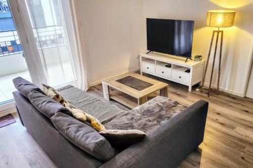 un salon avec un canapé et une télévision à écran plat dans l'établissement Modern 2BR balcony secured parking metro 14, à Saint-Ouen